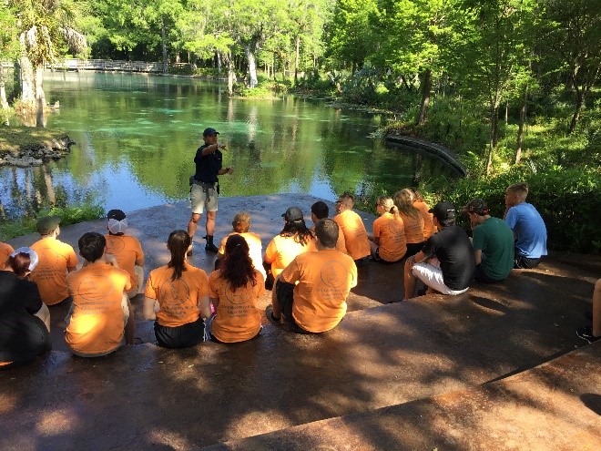 students listening to speaker near spring