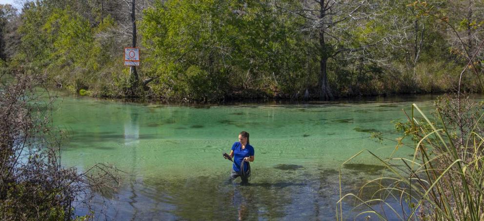 District staff member collecting water samples in river