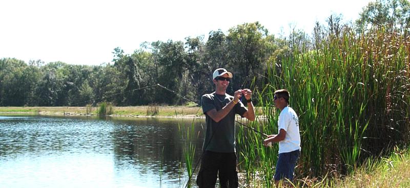 two teens fishing on pond shore