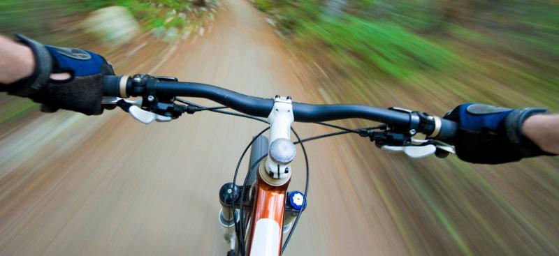 view of handlebars and trail looking down as a bike rider