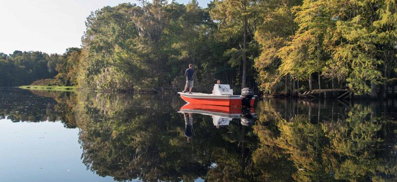 man on small red boat on river