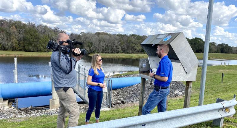 News crew interviewing District staff beside water structure