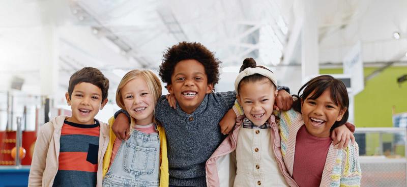 happy kids in classroom with arms around each other
