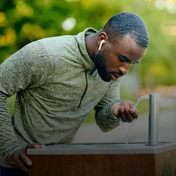athletic man drinking from outdoor water fountain