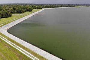 Aerial view of reservoir with green grass and tree on edge