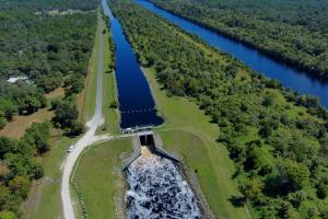 Aerial view of water going through spillway surrounded by forest