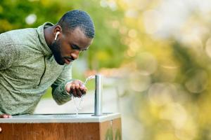 athletic man drinking from outdoor water fountain